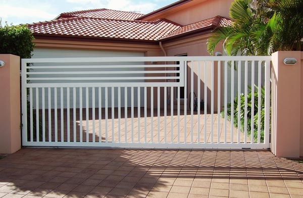 White aluminium sliding gate between rendered piers