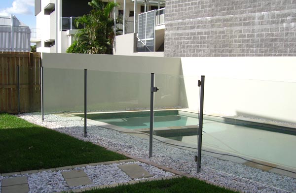 Semi-frameless glass pool fence around a backyard pool